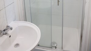 A glass-enclosed shower with a handheld showerhead and a wall-mounted control panel. - Sunlight Studio (London)