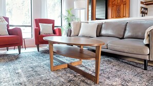 A living room with a wooden coffee table, red armchairs, a beige sofa, and a patterned rug. - Charming 4-bedroom family home in Beaverton with AC, fitness room, WiFi (Beaverton)