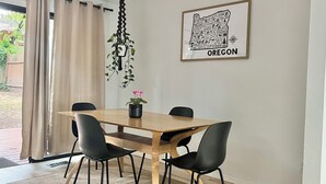 A dining area with a wooden table, black chairs, a hanging plant, and a framed map of Oregon on the wall. - Charming 4-bedroom family home in Beaverton with AC, fitness room, WiFi (Beaverton)