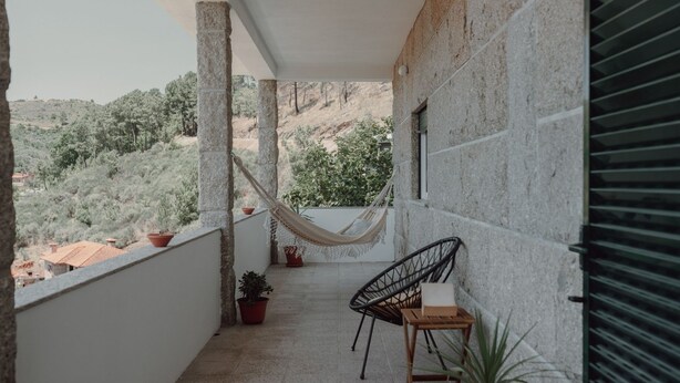 Un balcon avec un hamac, une chaise et des plantes en pot.