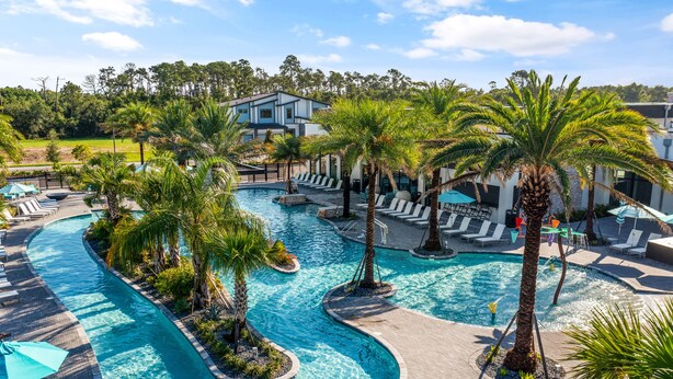 Un resort con una piscina grande, palmeras y zonas de descanso.