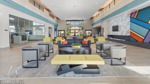 A spacious lobby with a central seating area, a reception desk, and a large window providing a view of the outdoors. - Epic Paradiso Mansion-Pool/Game Room/Theater-2 (Orlando)