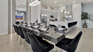 A modern dining area with a long table, black chairs, and a central island. - Epic Paradiso Mansion-Pool/Game Room/Theater-2 (Orlando)