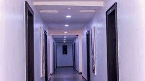 A long, narrow hallway with doors on both sides, recessed lighting on the ceiling, and a tiled floor. - HASB APARTMENTS (Lagos)