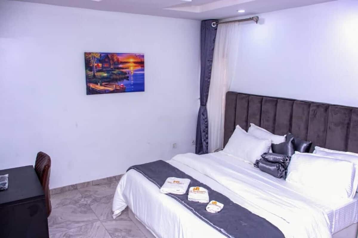 Une chambre d’hôtel avec un lit, un bureau, une chaise et un tableau au mur.