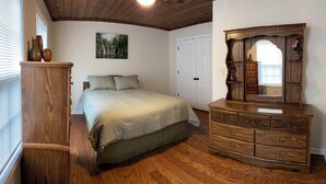 Un dormitorio con una cama, tocador y un cuadro en la pared.