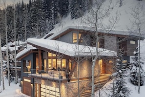 A modern multi-story house with a balcony, large windows, and a wooden exterior.