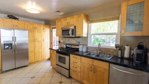 A kitchen with wooden cabinets, stainless steel appliances, and a window providing natural light. - Centrally Located Cottage Near Lake Trails Shops (La Mesa)
