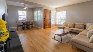 A living room with a sofa, coffee table, and dining area with chairs and a table. - Centrally Located Cottage Near Lake Trails Shops (La Mesa)