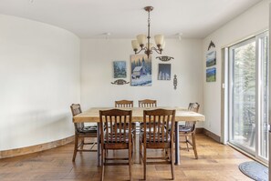 Un comedor con mesa y sillas de madera, una lámpara de araña y obras de arte en las paredes.