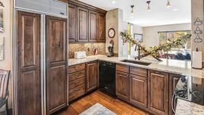A modern kitchen with wooden cabinets, a built-in dishwasher, and a large island with a sink. - Vantage Point Condo 304 | Spacious 3BR in Lionshead Village (Vail)
