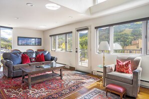 A spacious living room with a leather sofa, a coffee table, and a patterned rug.