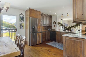 Una cocina moderna con armarios de madera, electrodomésticos de acero inoxidable y vistas a un paisaje montañoso.