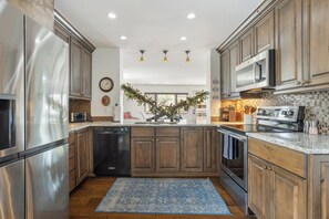 A modern kitchen with stainless steel appliances, wooden cabinets, and a central island.