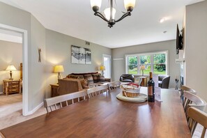Een ruime woonkamer met een eettafel, een zithoek en een groot raam met uitzicht op de omgeving.