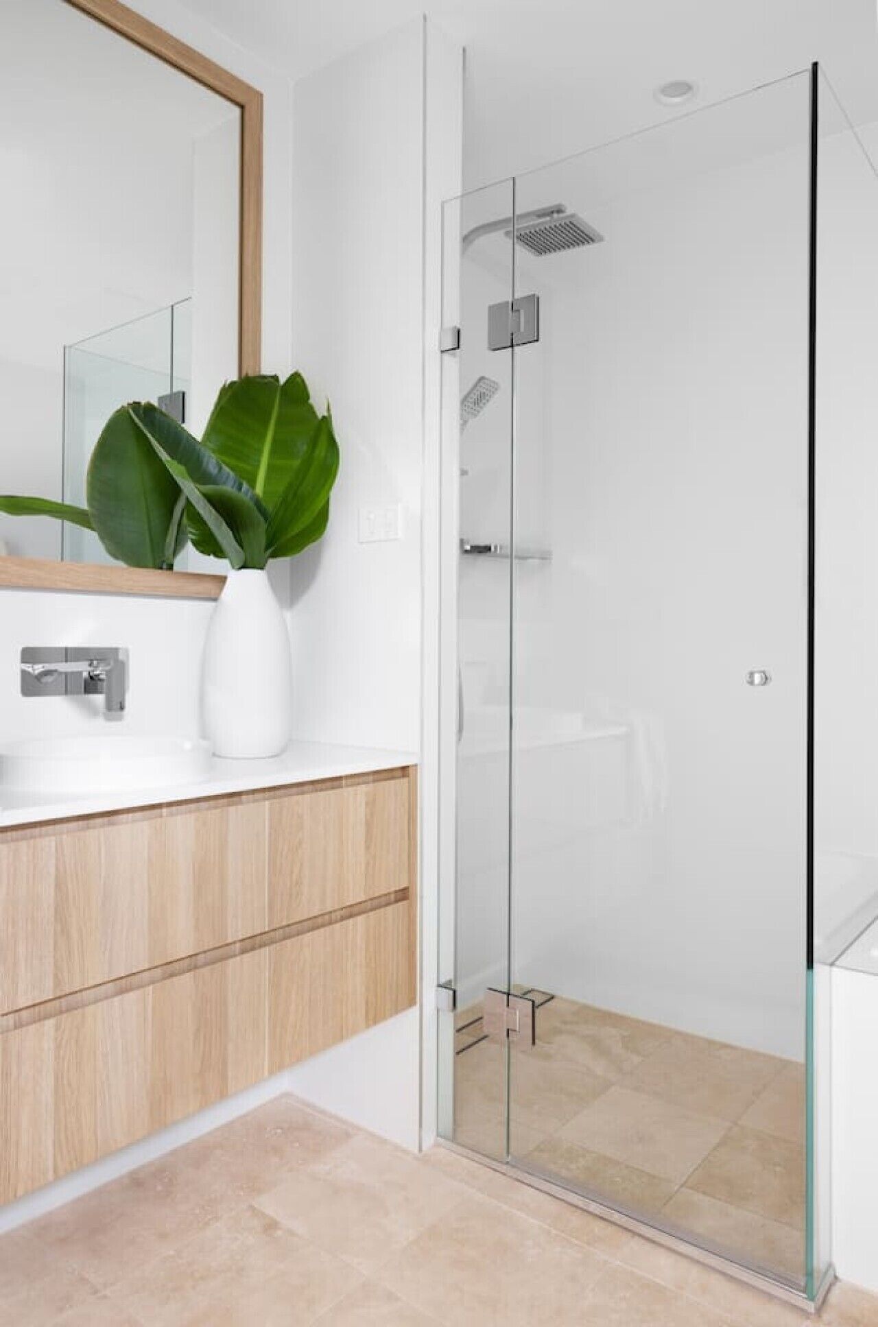 Une salle de bain moderne avec une douche à parois de verre, un meuble-lavabo en bois et un grand miroir.