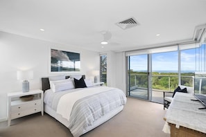 Une chambre moderne avec un grand lit, une table de chevet, une commode, une fenêtre donnant sur un beau paysage et un balcon avec une table et des chaises.