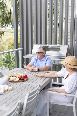An outdoor patio with a grill, dining table, and chairs.