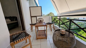 Un balcon avec une table en bois, des chaises et un panier en osier.