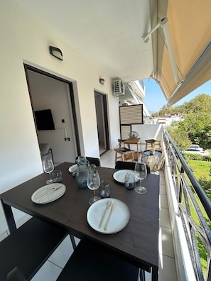 A dining area with a table set for four, a TV mounted on the wall, and an air conditioning unit. - JM Apartment in Kamena Vourla (Kamena Vourla)
