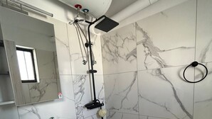 Une salle de bain avec un lavabo blanc, un miroir et des murs recouverts de carreaux de marbre.
