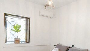 Une chambre à coucher avec un lit, des oreillers, une fenêtre avec une plante et un luminaire au plafond.
