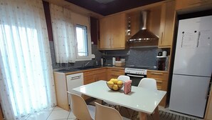 Una cocina moderna con una mesa blanca, sillas y un tazón de fruta.