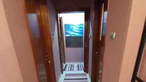 Un pasillo con alfombra a rayas, puertas de madera y vista al mar a través de una ventana.