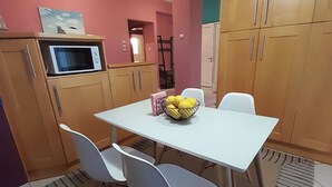 Un comedor con una mesa blanca, cuatro sillas blancas, un cuenco de limones y armarios de madera.