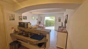 A kitchen with granite countertops, a microwave, a toaster, and a sink. There is a dining area with a table and chairs visible through an open doorway. - Résidence La Belle Poule 1172 (Sainte-Maxime)