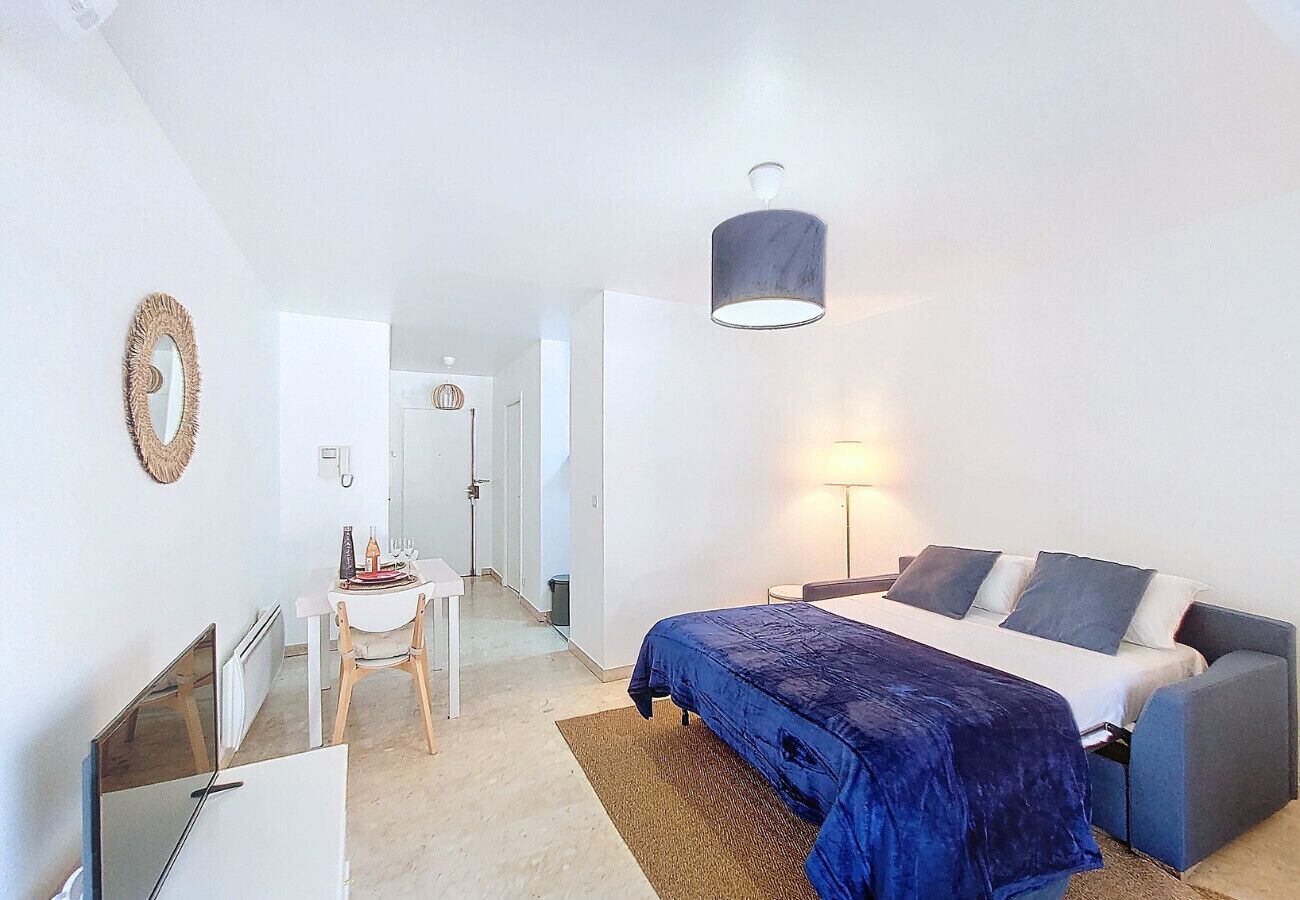 Een slaapkamer met een bed, een bureau en een stoel. Er staat een lamp op het bureau en een hanglamp boven het bed.