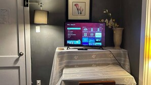 A television on a table with a framed picture above it.