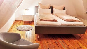A bedroom with a bed, a chair, and a nightstand.