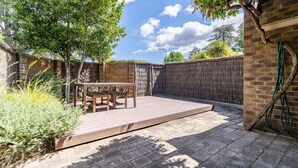 A patio with a wooden table and chairs, surrounded by a brick wall and a tree. - Charming two-story 2BR townhouse in Braddon (Braddon)