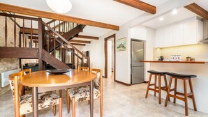 A modern kitchen with white cabinets, a stainless steel refrigerator, and a wooden dining table with chairs. - Charming two-story 2BR townhouse in Braddon (Braddon)