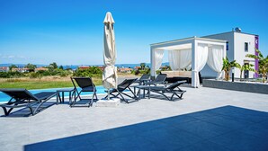 Un espace aménagé au bord de la piscine, avec des chaises longues et un auvent, offrant une vue panoramique.