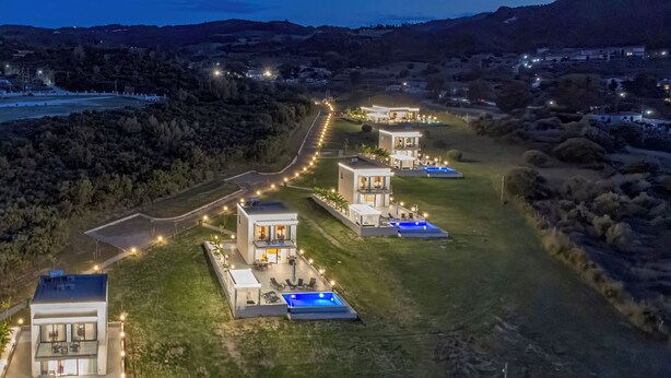 Un complexe résidentiel moderne composé de plusieurs maisons reliées par des allées, doté d’espaces de détente en plein air et de piscines.