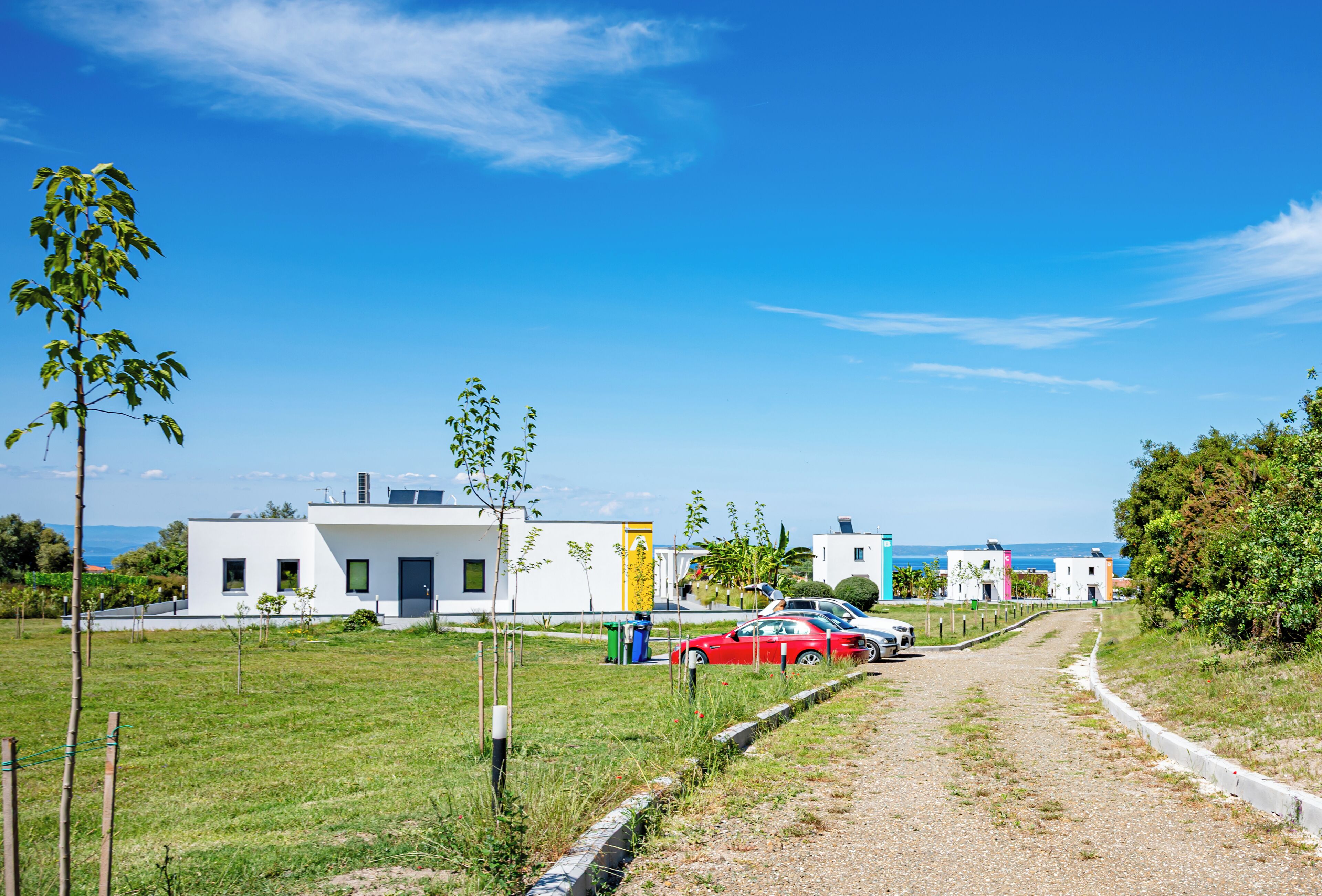 Et boligområde med moderne huse, en grussti og havudsigt.