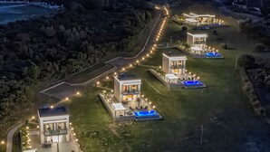 Un complexe hôtelier moderne doté de plusieurs villas, chacune offrant une piscine privée et un espace de détente extérieur.