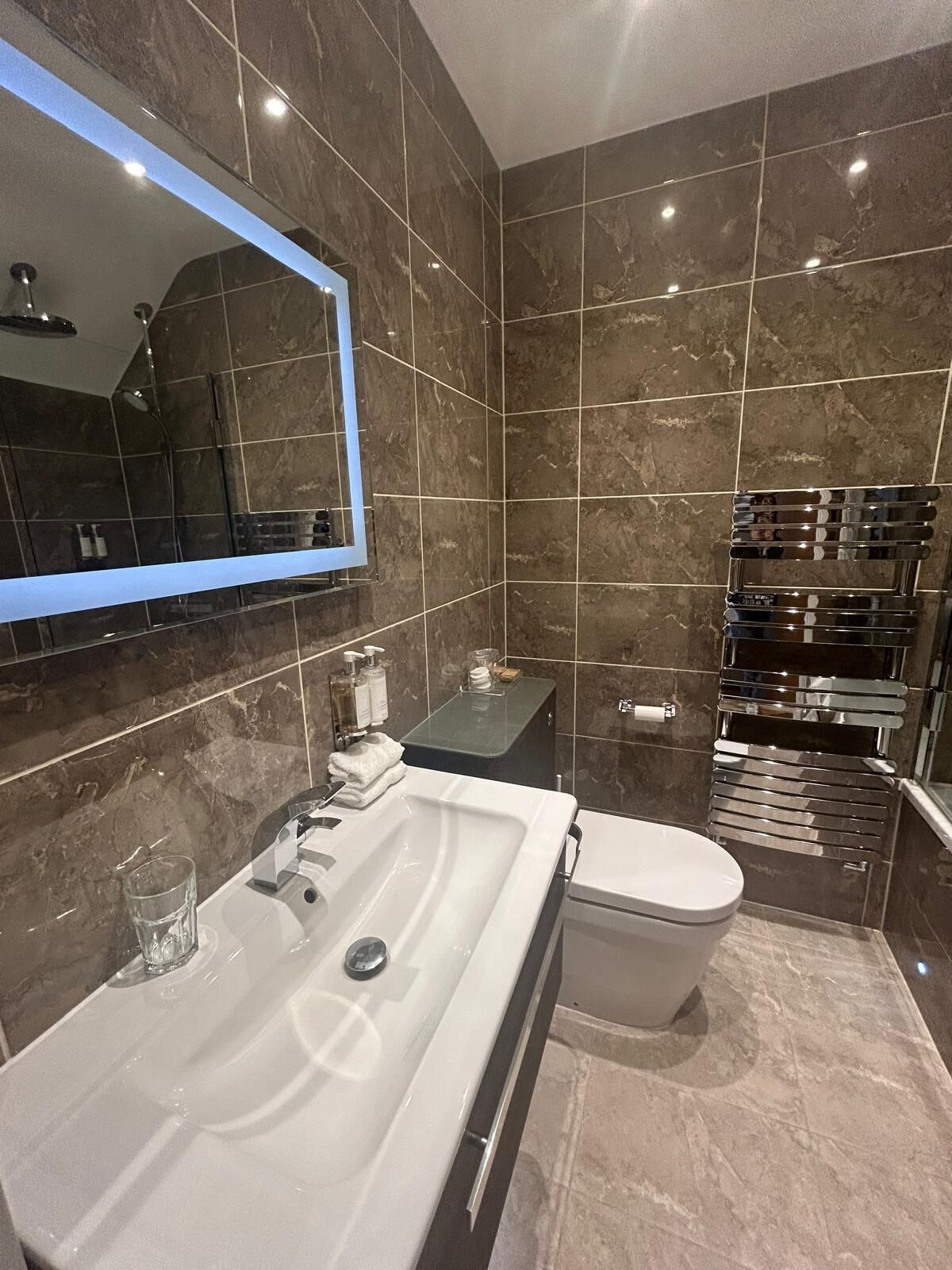 A modern bathroom with a white sink, mirror, and toilet.