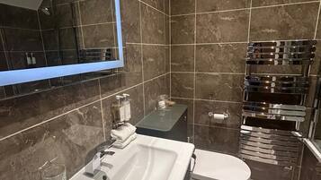 A modern bathroom with a white sink, mirror, and toilet.