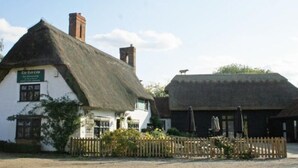 A traditional thatched-roof building with a sign reading "The Red Cow." - The Red Cow Inn (Royston)