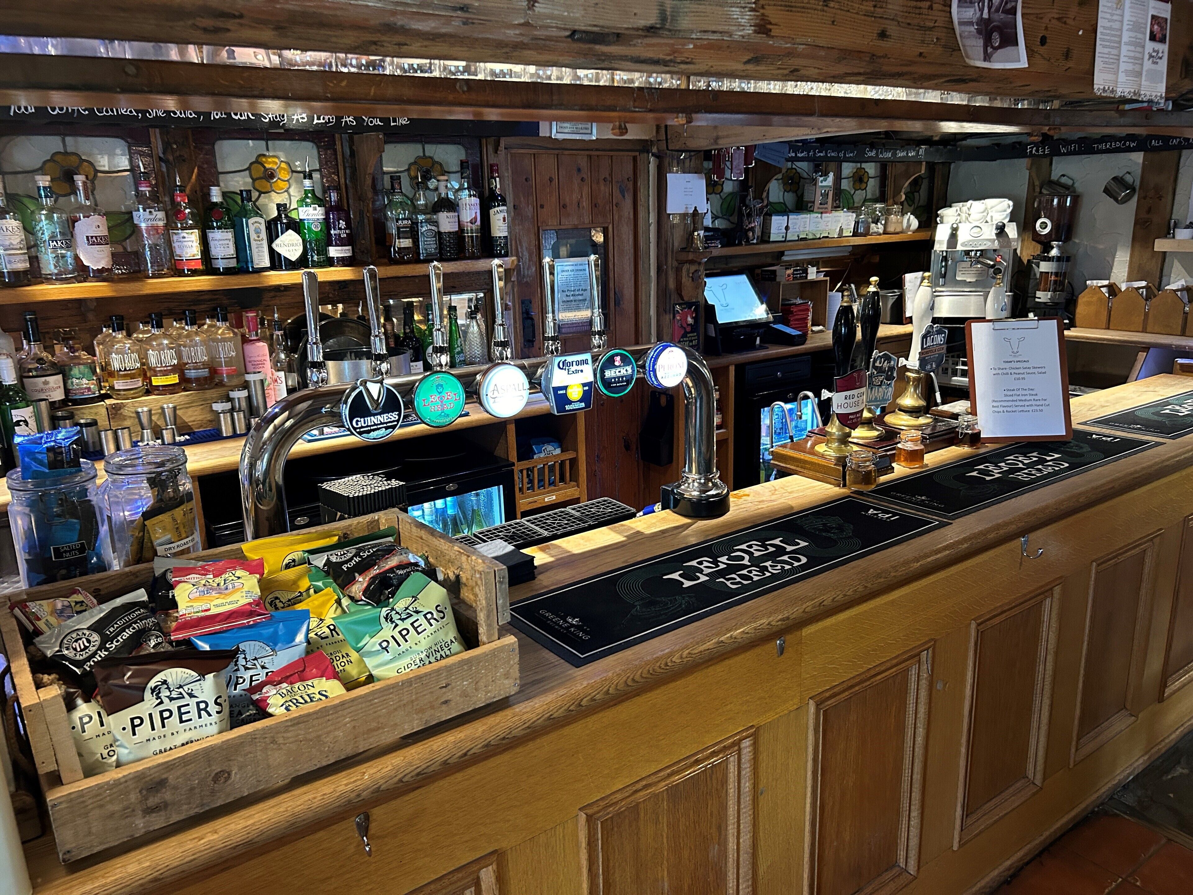 A bar area with multiple liquor bottles, a coffee machine, and a variety of snacks.