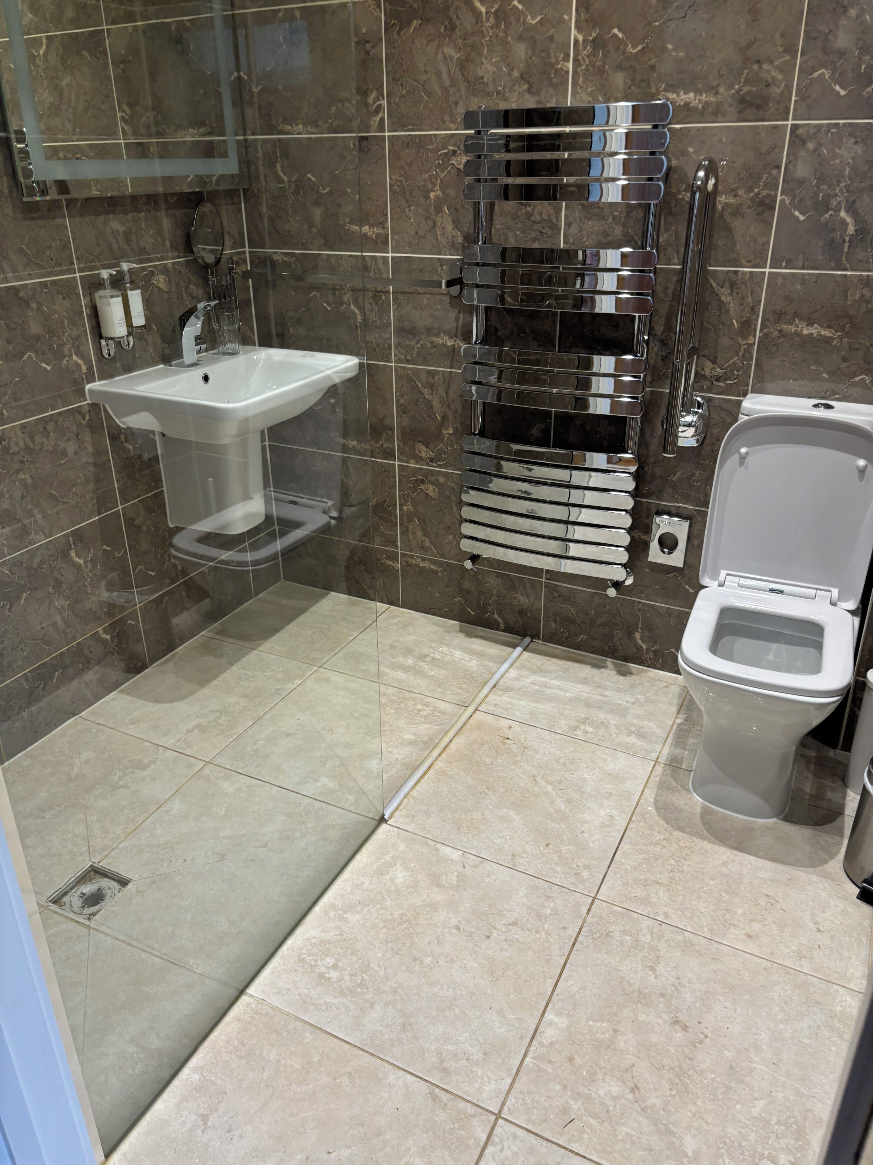 Un baño moderno con un lavamanos blanco, un inodoro y un perchero para toallas.
