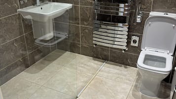 Un baño moderno con un lavamanos blanco, un inodoro y un perchero para toallas.