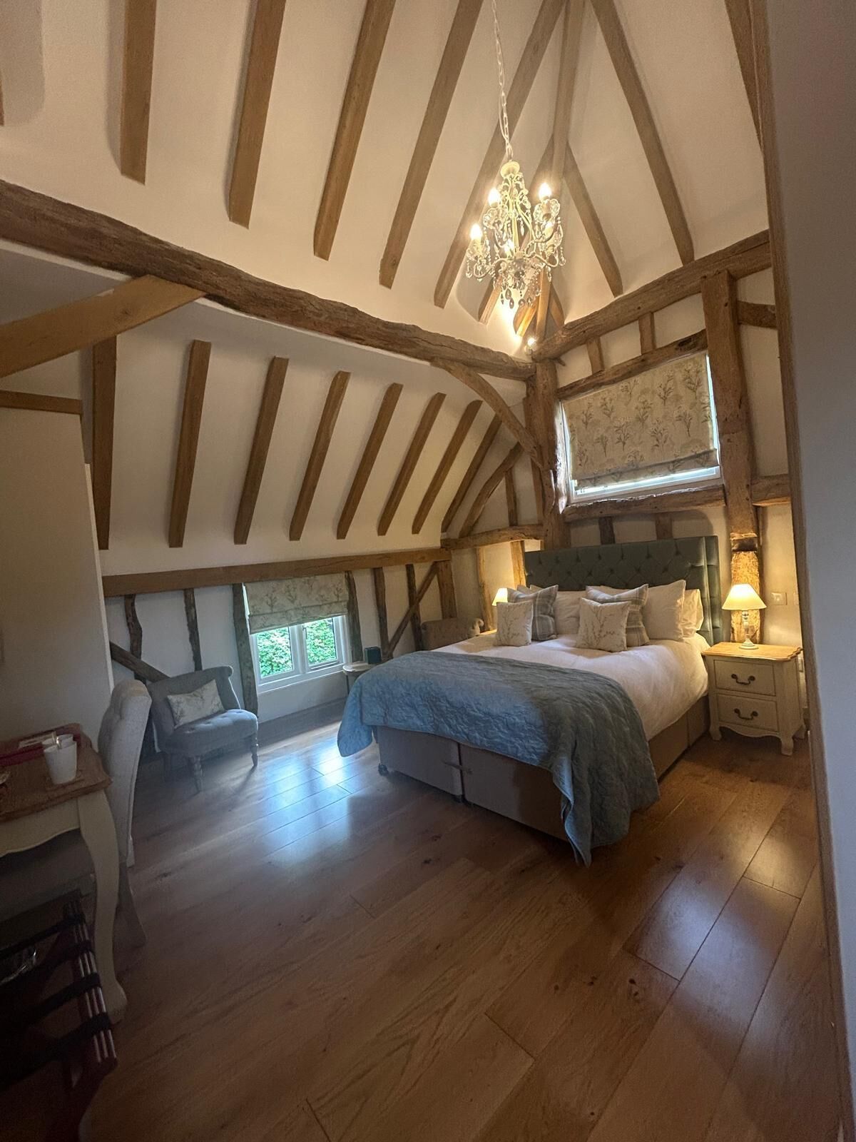 Un dormitorio con una cama grande, vigas de madera, una araña y una ventana con vistas.