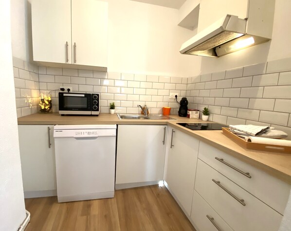 A compact kitchen with white cabinets, a microwave, a dishwasher, and a sink.