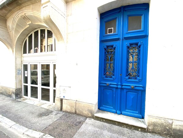 Un bâtiment à la façade blanche et à la porte bleue, ornée de motifs en métal.