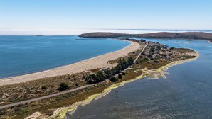 Vista aérea de una zona costera con una playa arenosa, una carretera y un pequeño poblado con edificios.