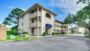 A multi-story building with a central entrance, balconies, and a covered area with a blue awning. - Little River Condo w/ Pool Access: 5 Mi to Beach (Little River)
